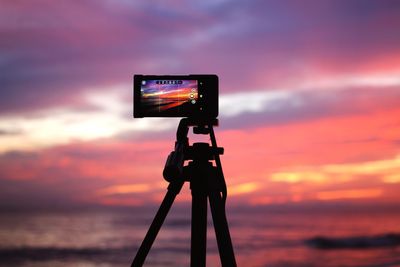 Low angle view of camera against sky at sunset