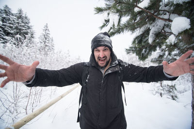 Young man with arms outstretched standing on snow