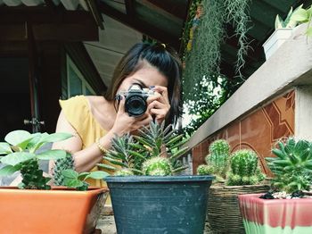 Woman taking photo small tree with camara with happiness.