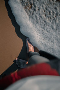 Low section of person standing on shore at beach