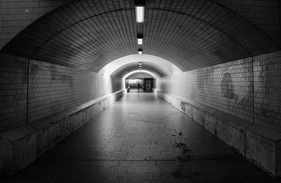 Woman walking in illuminated tunnel