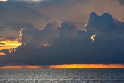 Scenic view of sea against dramatic sky during sunset