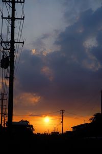 Low angle view of silhouette electricity pylon against sky during sunset