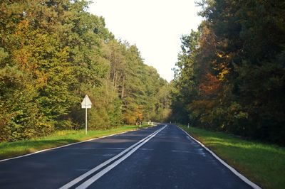 Road amidst trees against clear sky during autumn