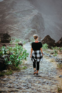 Rear view of woman walking on footpath towards mountains