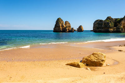 Rocks on beach against clear sky