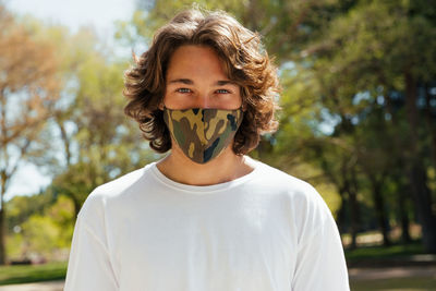 Portrait of smiling young man standing against trees