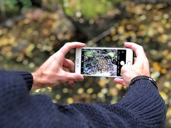 Cropped hands of man photographing with mobile phone