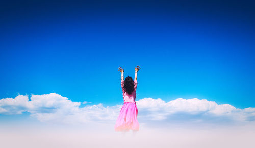 Rear view of woman standing against blue sky