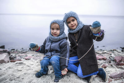 Girl in knitted grey hat sharing gloves with her frozen brother