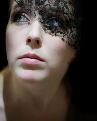 Close-up of young woman wearing veil against black background