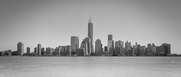 Cityscape by sea against clear sky