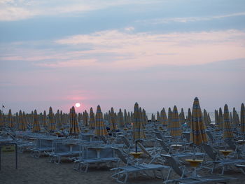 Sailboats moored in sea against sky during sunset