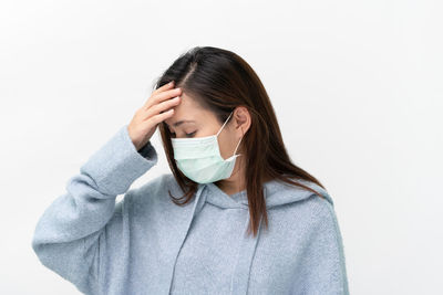 Portrait of woman covering face against white background