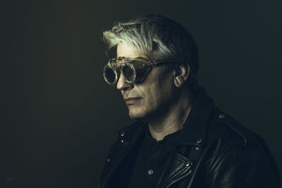 Portrait of man wearing sunglasses against black background