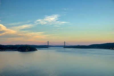 View of suspension bridge over sea against sunset sky