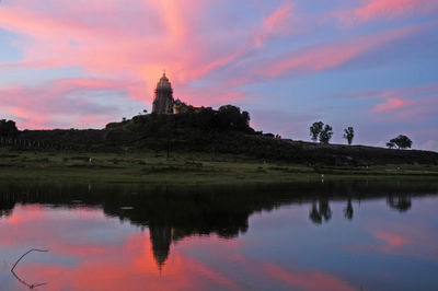 Reflection of building on lake against sky during sunset