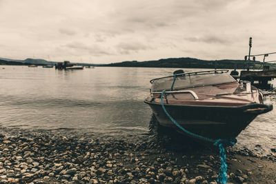 Boats in lake against cloudy sky