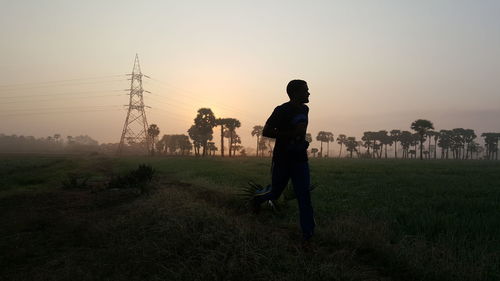 Man jogging in field against clear sky in morning