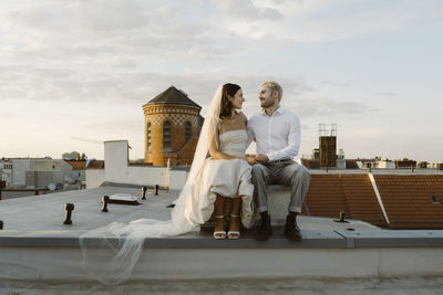 Young male and female married couple sitting together on rooftop