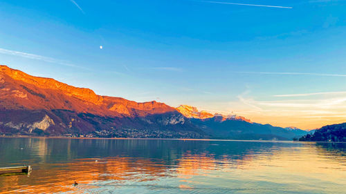 Scenic view of lake by mountains against sky during sunset