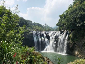 Scenic view of waterfall against sky