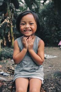 Portrait of smiling cute girl sitting on rock