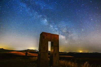 Old monument on field against starry sky