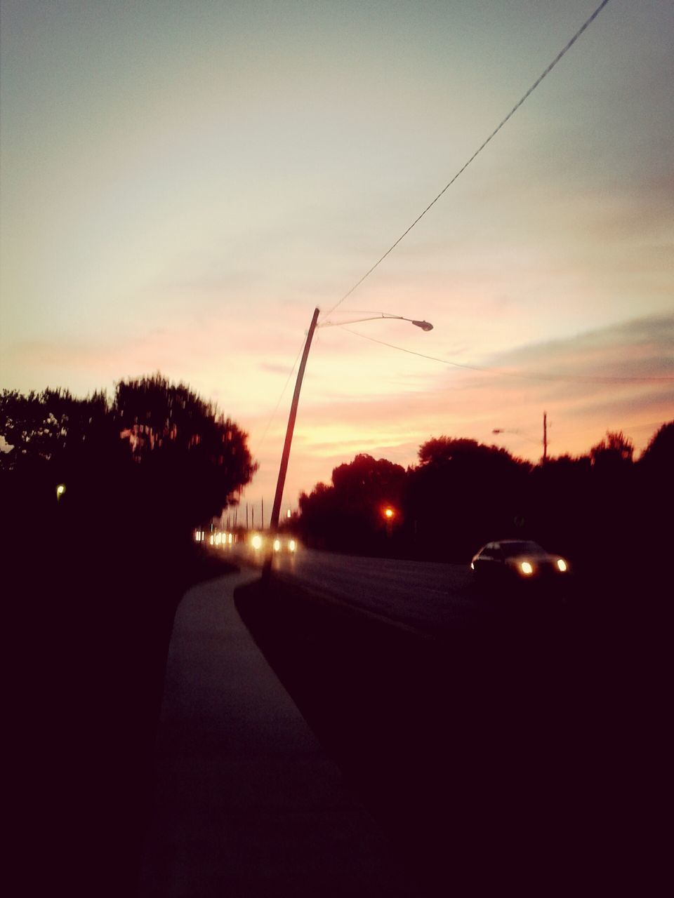 sunset, silhouette, tree, electricity pylon, power line, sky, street light, electricity, tranquility, road, orange color, tranquil scene, connection, beauty in nature, scenics, nature, the way forward, transportation, dusk, dark