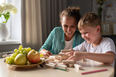 Happy mother and son playing on table