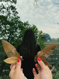 Cropped hand of woman holding leaves while standing outdoors