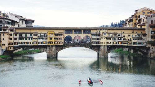 People on bridge over river against sky