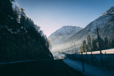 Road amidst trees against clear sky during winter