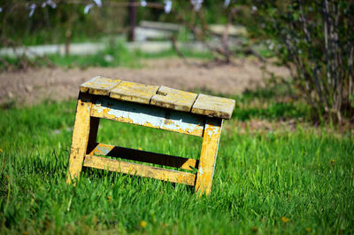 Close-up of empty park bench on field