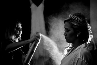 Hairdresser spraying on woman hair at home