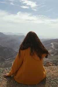 Rear view of woman looking at mountain against sky