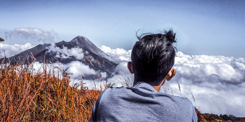 Rear view of man standing on snowcapped mountain
