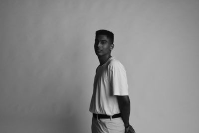 Portrait of young man standing against wall