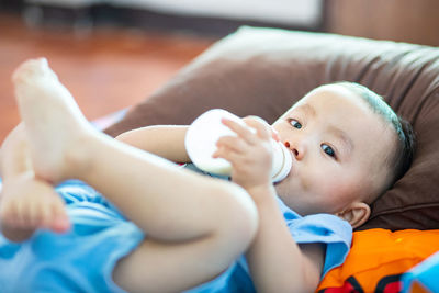 Portrait of cute baby lying on bed who sucking milk