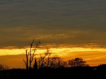 Silhouette bare trees against dramatic sky during sunset