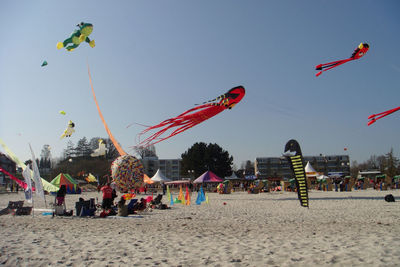 Kites flying over sandy beach against clear sky