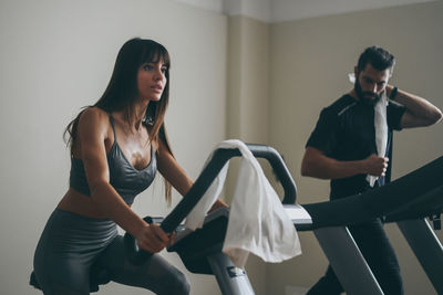 Determined couple working out in gym. fit boy and girl doing exercise on cyclette and tapis roulant.