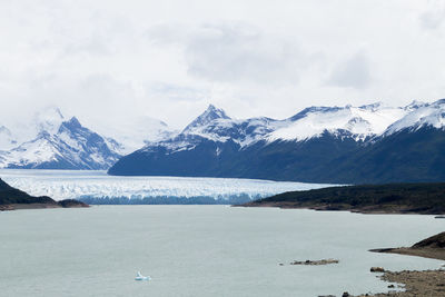 Scenic view of snowcapped mountains by sea against sky