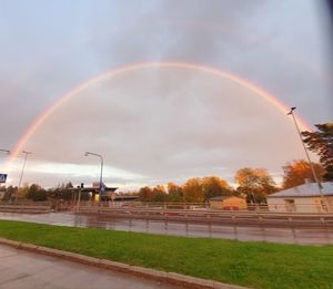 Rainbow over street against sky