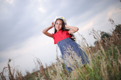 Portrait of smiling cute girl standing amidst plants on field during sunset