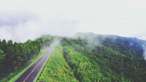 High angle view of empty road leading towards green mountains