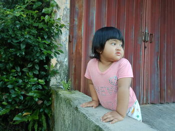 Cute girl looking away while sitting outdoors