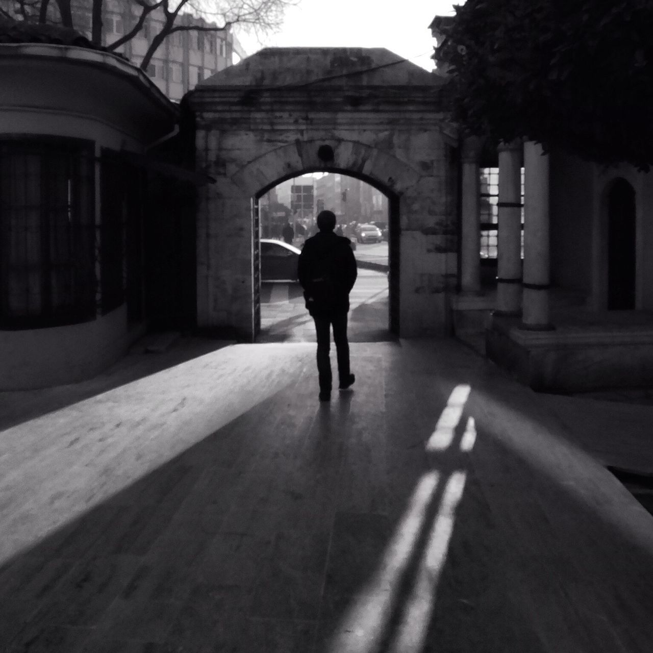 architecture, built structure, building exterior, walking, full length, the way forward, rear view, men, lifestyles, street, building, arch, day, city, person, shadow, cobblestone, diminishing perspective