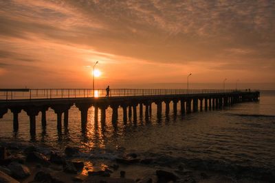 Pier over sea against sky during sunset