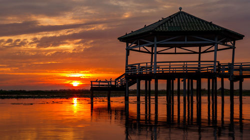 Pier over sea against sky during sunset